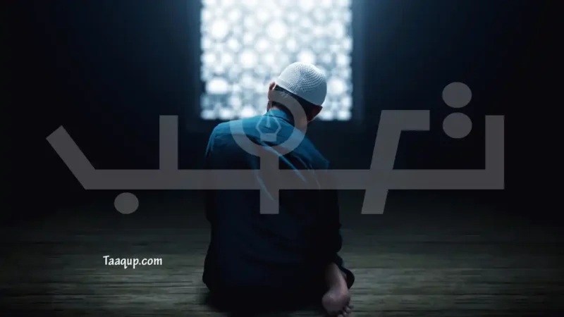 كيفية قيام الليل؟.. عدد ركعاته وأفضل الأدعية فيه 1 لقطة من الخلف لرجل مسلم يرتدي قبعة صلاة جالسًا على سجادة الصلاة في غرفة مظلمة، ينظر نحو نافذة مضيئة مزخرفة، مما يرمز إلى انتظار الفجر والنور بعد صلاة الليل.